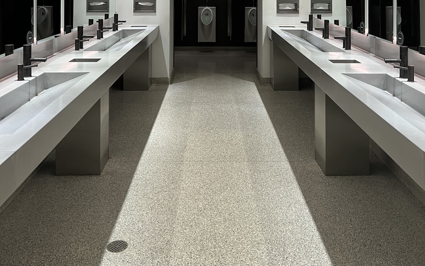 A commercial washroom with basins, mirrors and wall-mounted dispensers